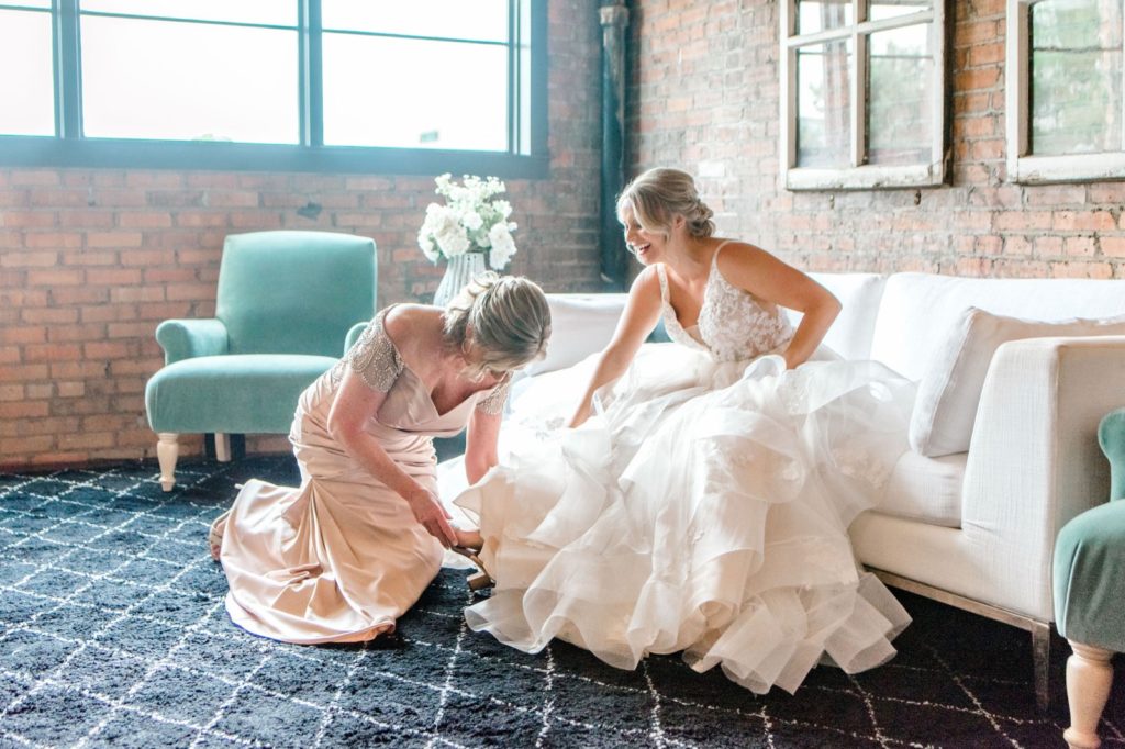bride getting dressed with help from mom
