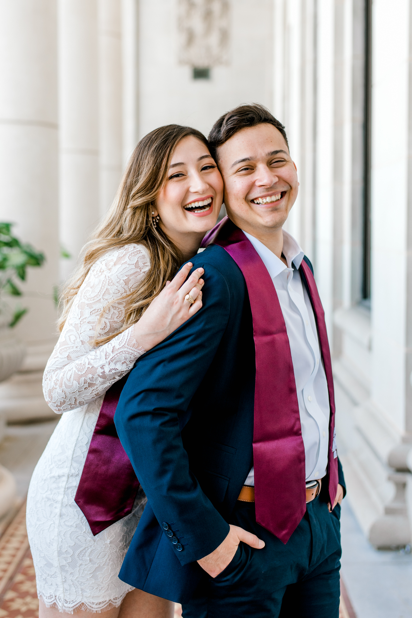 couple posing at Texas A&M administration building in graduation stoles