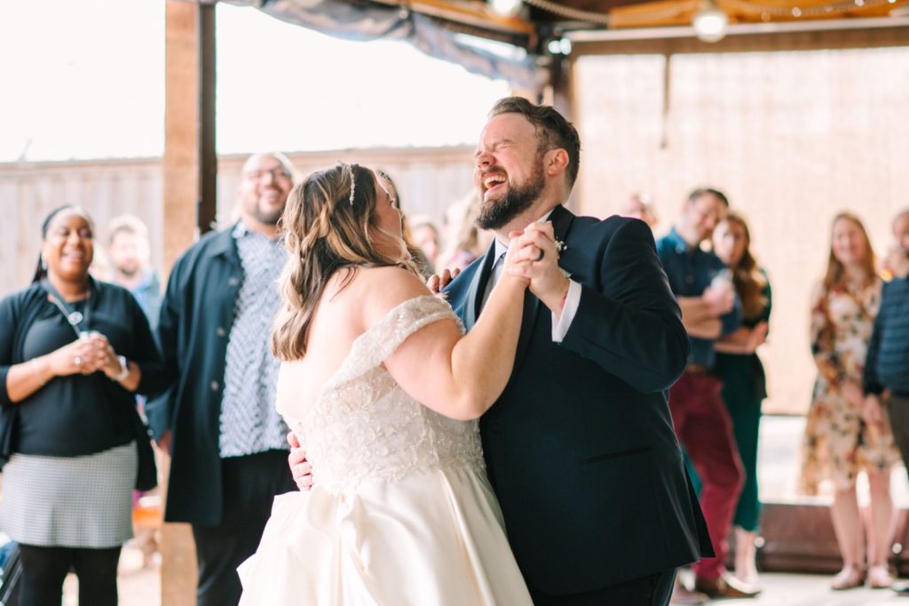 A newlywed couple laughing as they share their first dance.