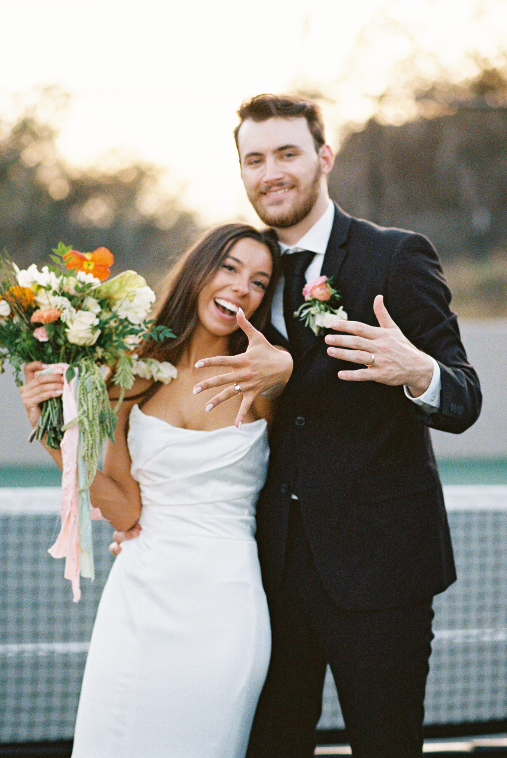 Newly married couple showing off their rings to the camera during sunset. Captured on 35mm film.